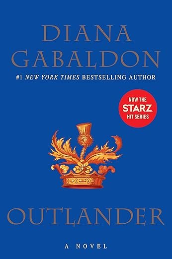 Blue book cover of 'Outlander' by Diana Gabaldon features a golden crest and a red circle noting its adaptation into a Starz series, conveying historical drama.