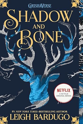 Cover of 'Shadow and Bone' by Leigh Bardugo features a blue stag with antlers, intricate patterns, and bold golden title. Netflix adaptation noted. Elegant, mysterious tone.
